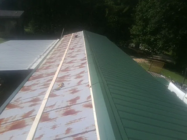 Old rusted panels beside newly installed green metal roofing — Wind Damage Roof Repair by Roofing Brothers in Nashville